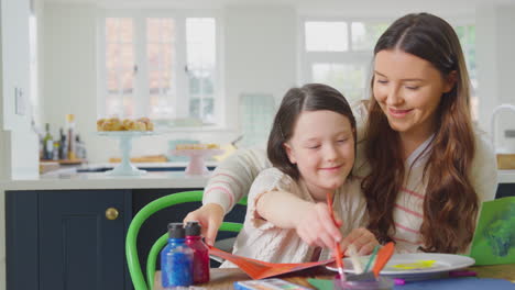 Madre-E-Hijas-Sentadas-Alrededor-De-Una-Mesa-En-Casa-Haciendo-Manualidades-Haciendo-Tarjetas-De-Felicitación-Juntas