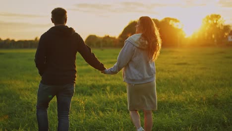 una pareja caminando de la mano al atardecer.