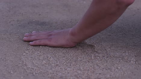 person's hand touching sand