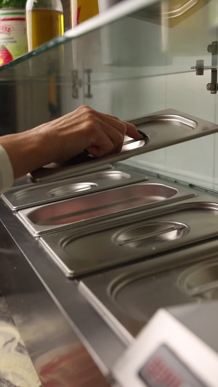Primer plano de una mano abriendo recipientes de comida de acero inoxidable en la cocina