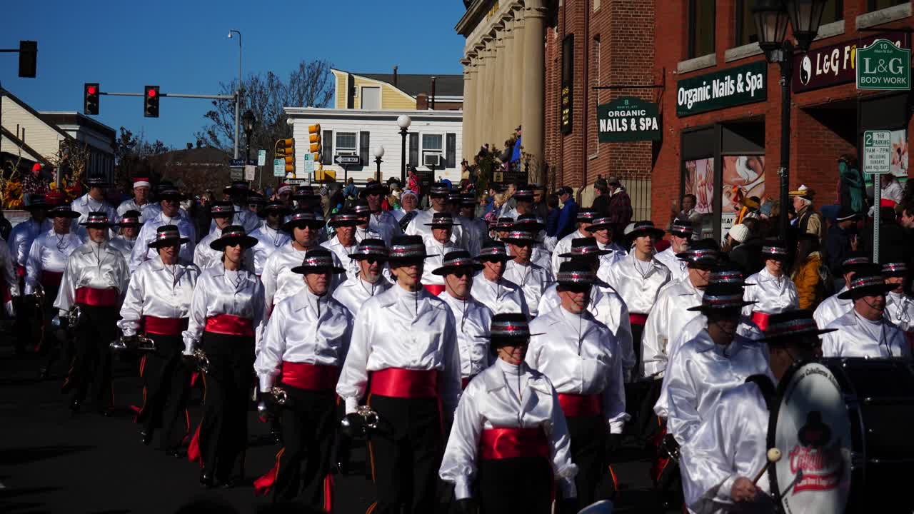 Snare Drum Marching Band dressed in Red and White playing percussions and drums, marching down the main street during the Thanksgiving Parade 2019 in Plymouth, Massachusetts