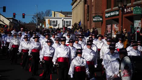 snare drum marching band dressed in red and white playing percussions and drums, marching down the main street during the thanksgiving parade 2019 in plymouth, massachusetts
