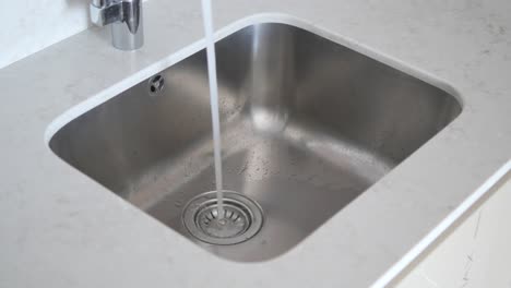 water running into a stainless steel kitchen sink