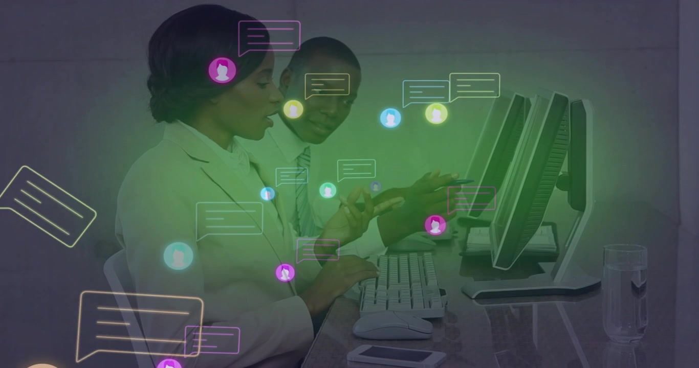 Woman tapping smartphone and man typing at office desk, spawning chat bubbles managing conversation
