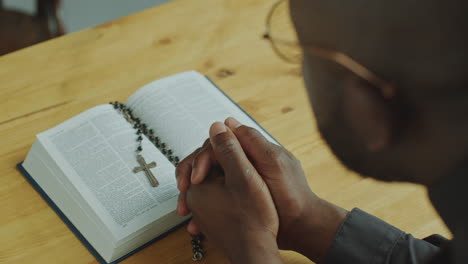 black pastor reading prayer in opened holy bible at the altar