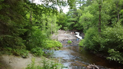 aerial drone shot of the little east river at stubb’s falls as a group of people relax on the rocks enjoying a beautiful day outdoors at arrowhead park, ontario, canada