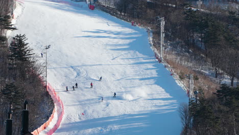 people skiing down on extreme run or track course at alpensia ski resort in slow motion - aerial high angle