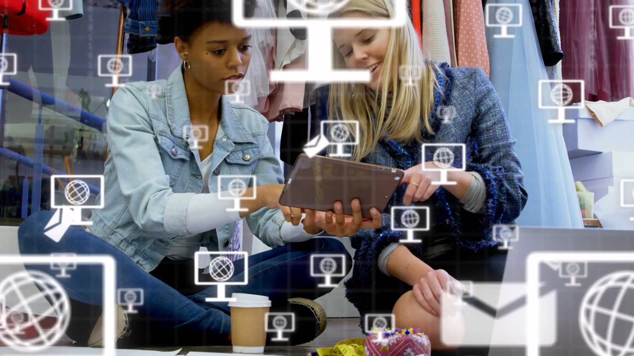 Two designers tapping tablet examining looks as monitor and mail icons growing around it for retail