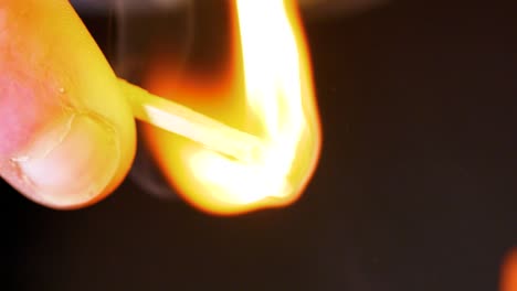 hd super slow motion cinematic macro shot of a match being lit, in a dark room