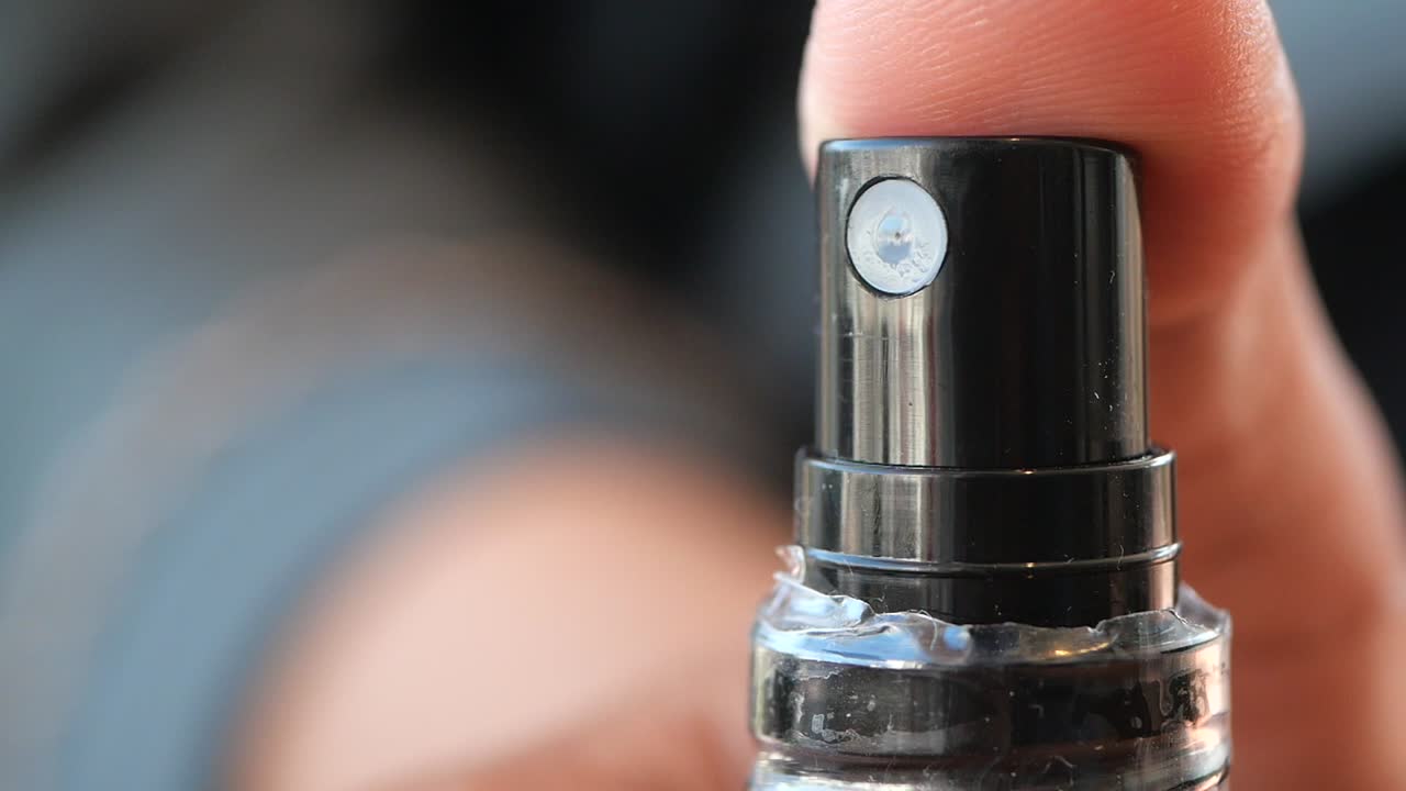 Close-up of a spray bottle nozzle held by a finger