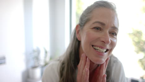 Mujer-Caucásica-Con-Pelo-Gris-Sonriendo,-Tocando-La-Cara