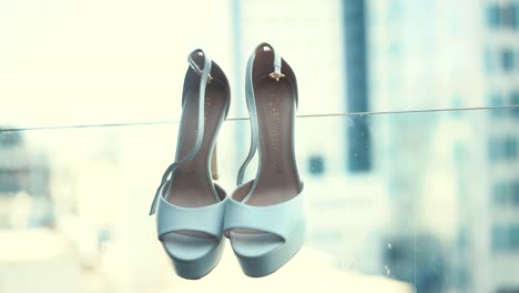 A-hanging-white-pair-of-wedding-hill-shoes,-close-up-shot,-slow-motion