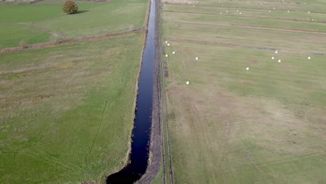 Areal-drone-footage-of-water-channel-and-vast-farming-fields-with-autumn-colors-taken-at-place-called-Uetz-in-Brandenburg,-Germany