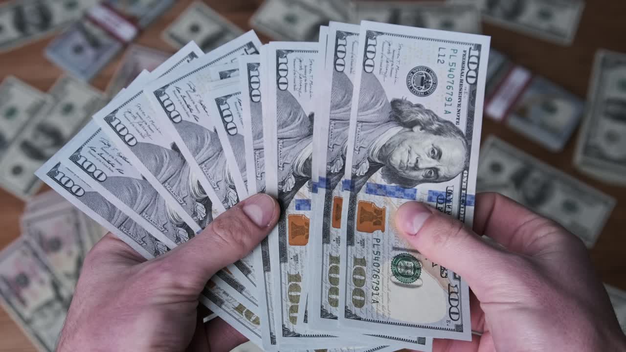 dólares en manos masculinas en el fondo de la mesa con dinero