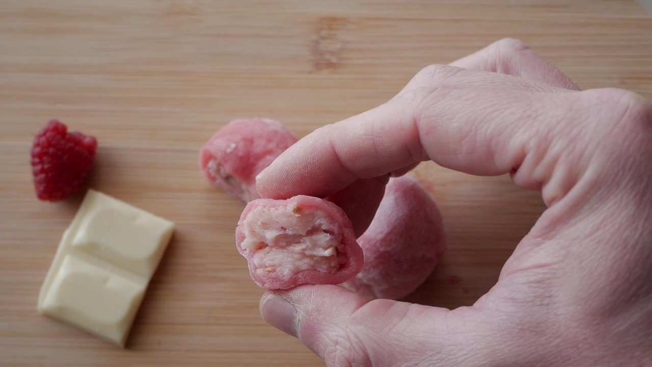 Fresh strawberry mochi with white chocolate filling, close-up of bite