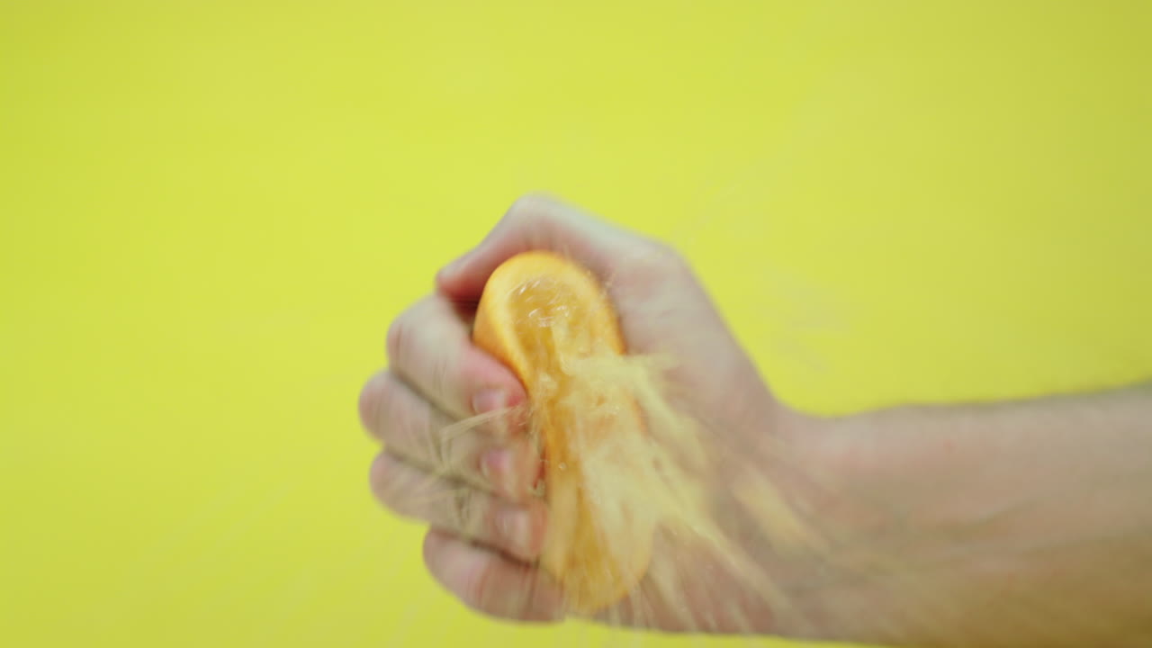 남자가 짜낸 신선한 오렌지, 주스가 카메라 렌즈로 날아가고 슬로우 모션 영상