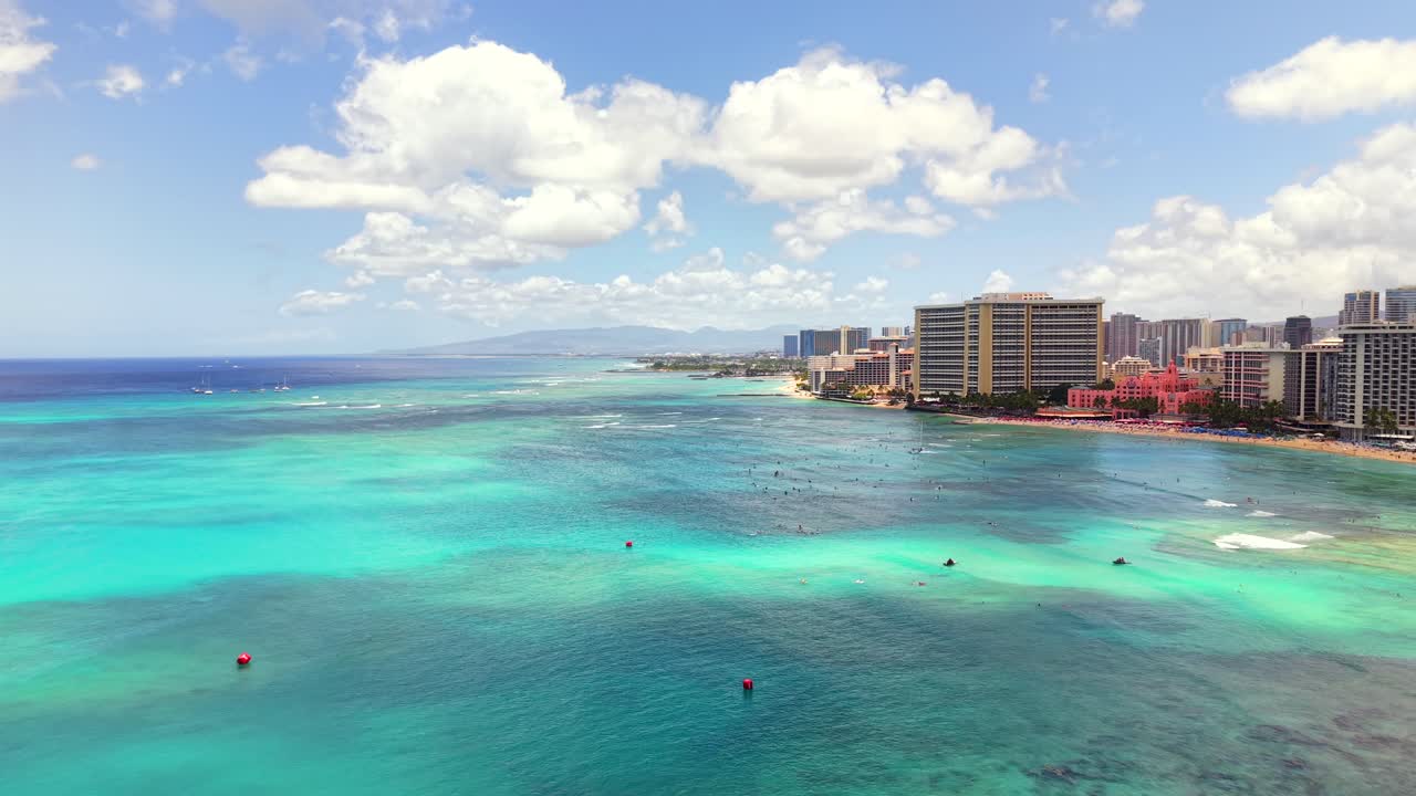 Waikiki beach with surfers, hotels, and turquoise ocean in Honolulu, aerial view