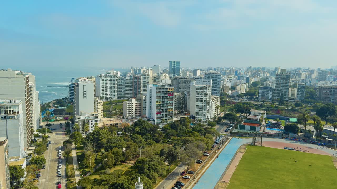 Wide cityscape with downtown skyscrapers, river, and distant mountains under clear sky, estabilshing static of Lima Peru