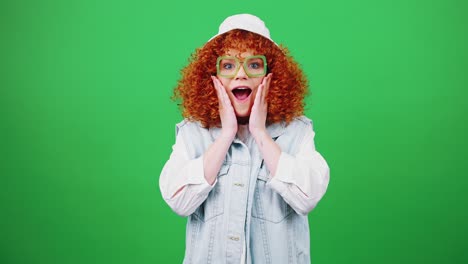 young cute redhead curly woman wearing panama hat and eyeglasses looking at camera and celebrating win