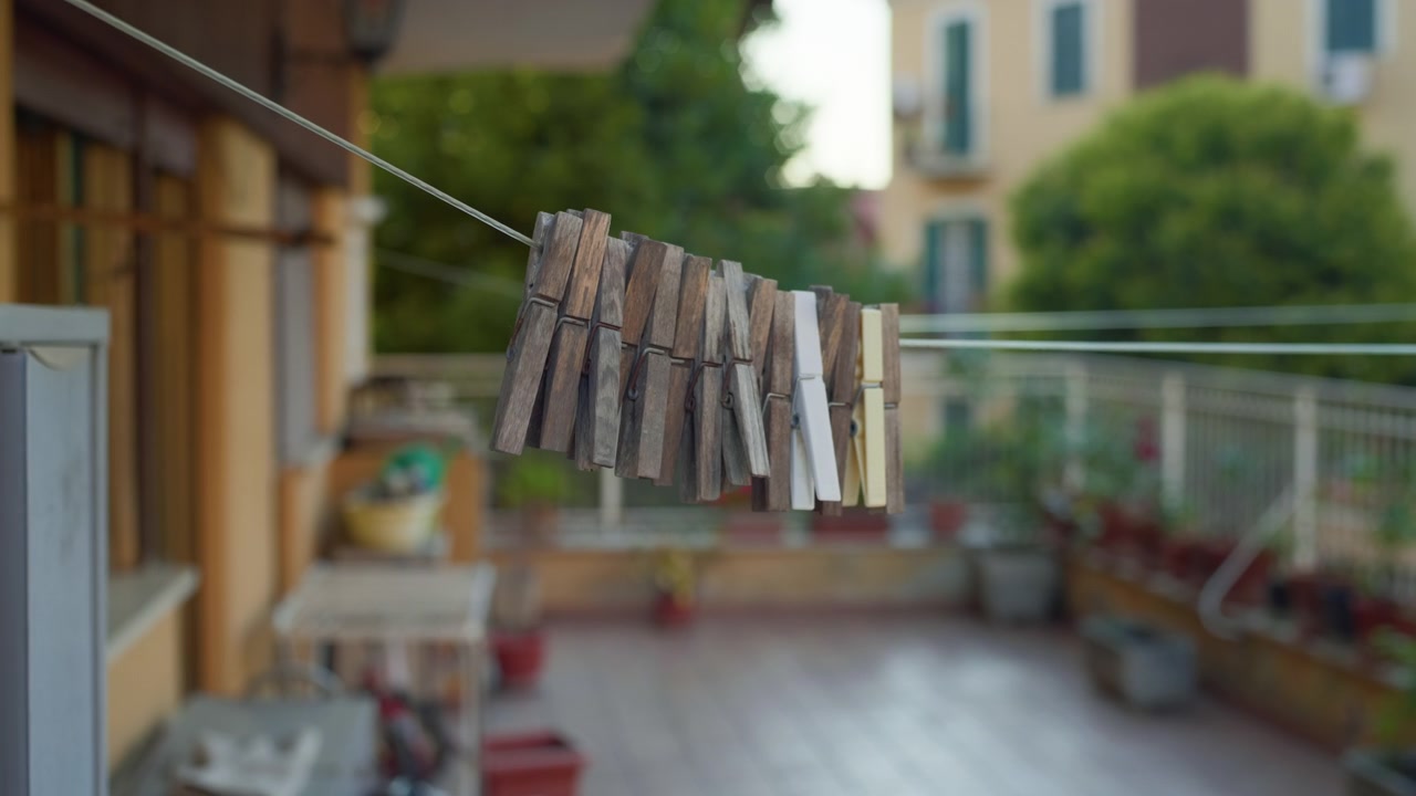 Stendibiancheria con mollette, tramonto, balcone, ripresa a mano in movimento. Vista diurna serale di una fila di mollette su un filo che si muove da sinistra a destra