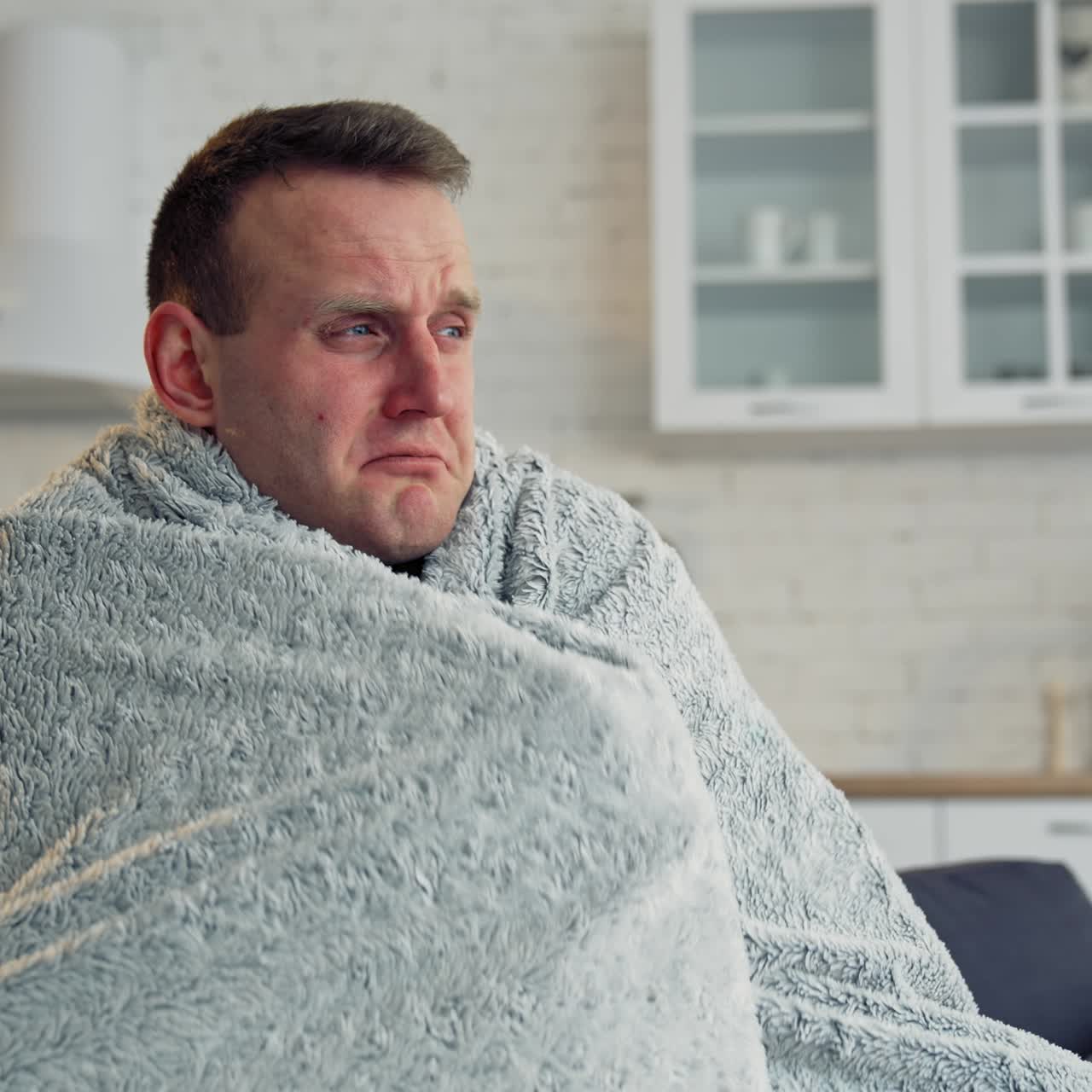 Sick man covered with warm blanket. Young man has a terrible headache and feeling ill at home. Infected man with virus. Coronavirus concept