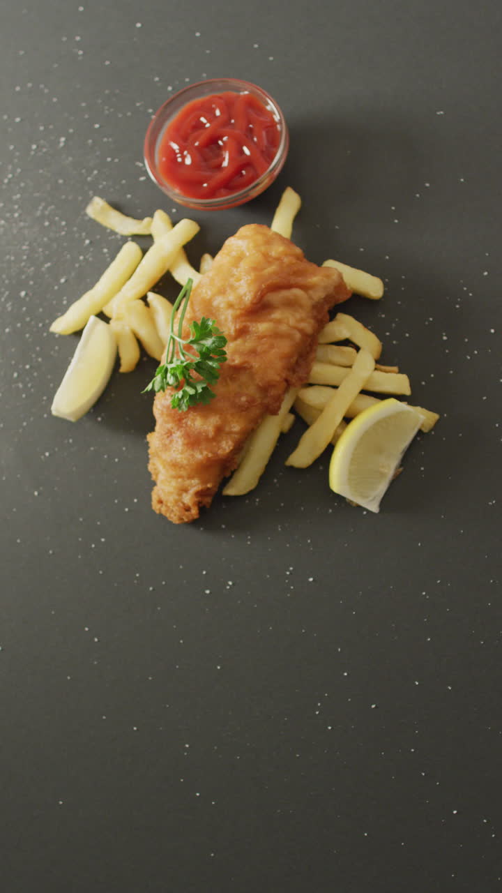 Vertical video of fresh homemade fried fish and chips on grey background