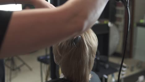 Professional-hairdresser-using-a-hairdryer-after-haircut.-Young-woman-getting-her-hair-dressed-in-hair-salon.-Hair-stylist