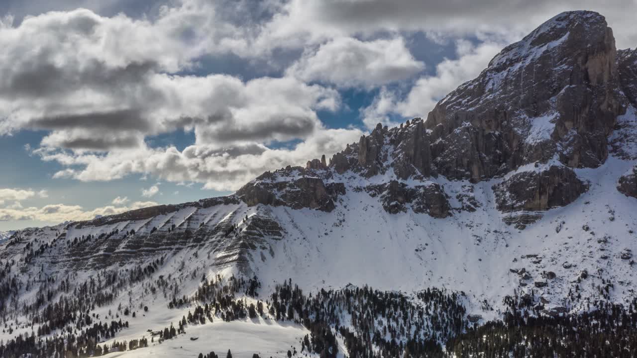 The Peitlerkofel a solitary mountain standing between Val Badia to the east and the Villnöß valley to the west, in the very north of the Dolomites. Snow-covered forest and hills. White clouds above.