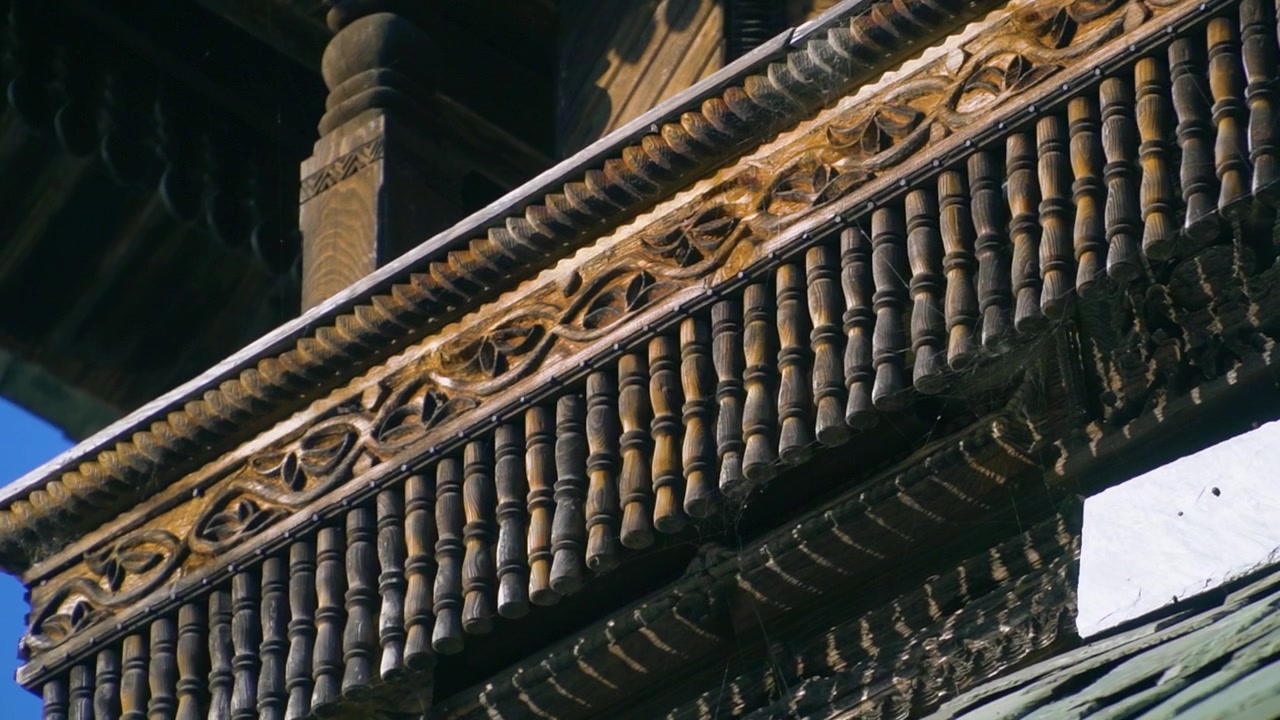 A cinematic slow motion shot through carved pillars revealing the intricate wooden balconies and slate roof of the historic Prashar Rishi pagoda temple in Mandi, Himachal Pradesh.