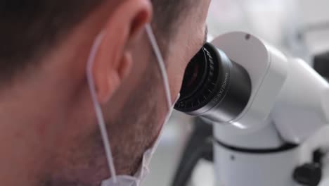 parte del dentista mirando a través del microscopio dental