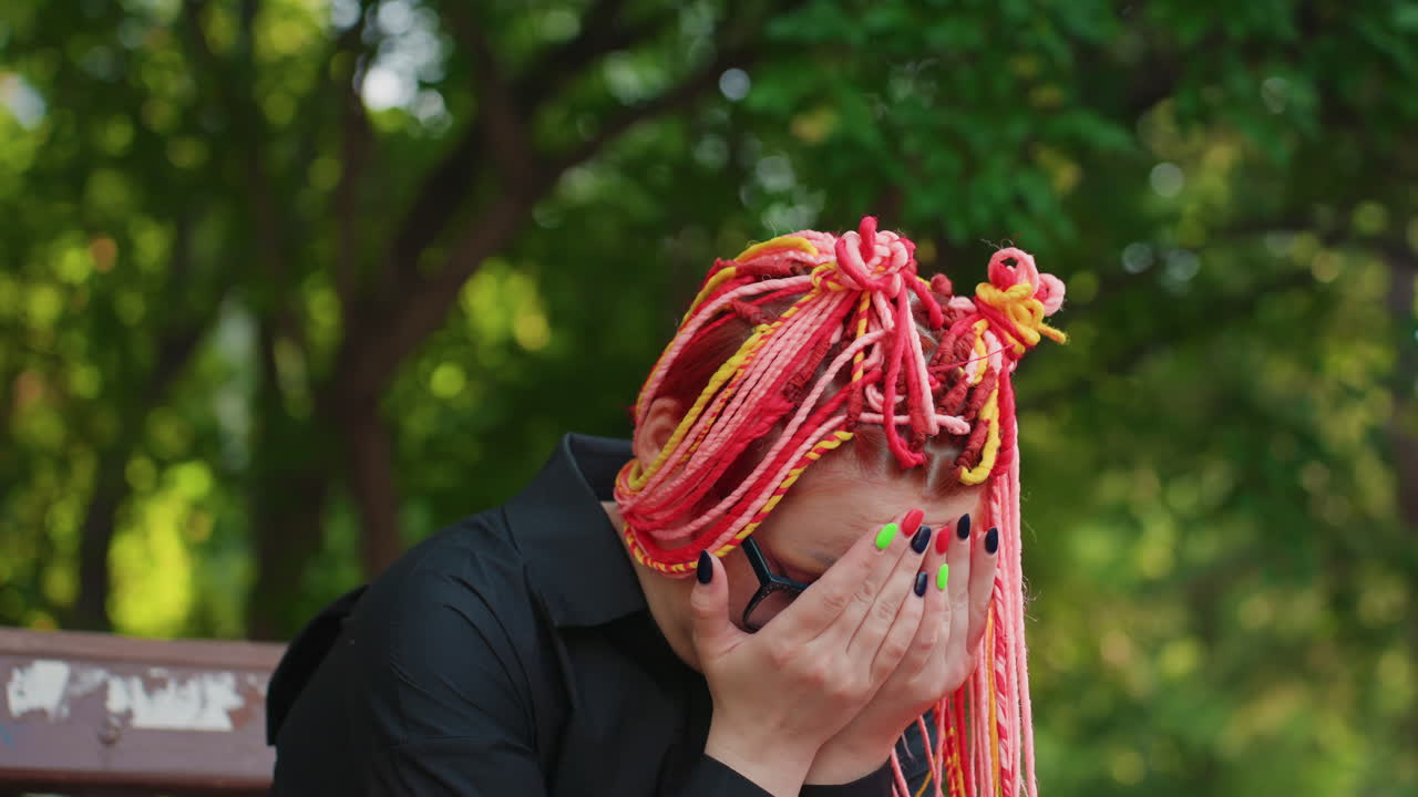 야외에서 괴로움을 표현하는 감정적인 여성, 평화로운 공원 환경에서 압도적인 감정을 드러내는 여성, 자연 속에서 땋은 머리와 안경을 쓴 여성이 날 것의 감정을 표현하고 있어요.