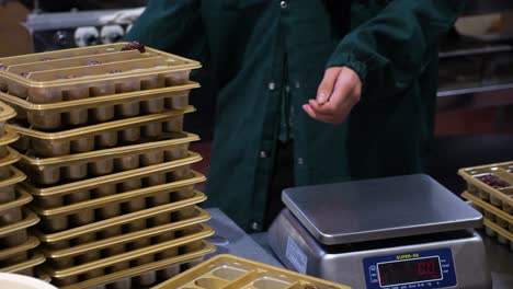 cinematic shot of fresh and best quality dates after being filled in a designed plastic boxes being measured by factory worker on a weighing machine in a dates factory