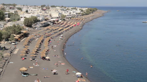 toma de ángulo alto de la playa de venta ambulante negra de kamari en la isla de santorini, grecia