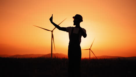 man taking selfie at wind farm sunset