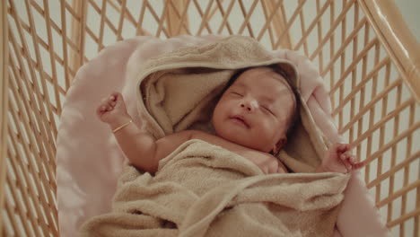 newborn infant baby peacefully sleeping on wooden cradle while swinging, cinematic top down view