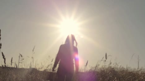 Woman-walking-through-farmers--field-at-sunset