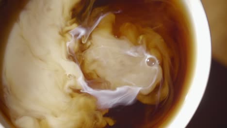 cream swirls in a cup of coffee in super slow motion