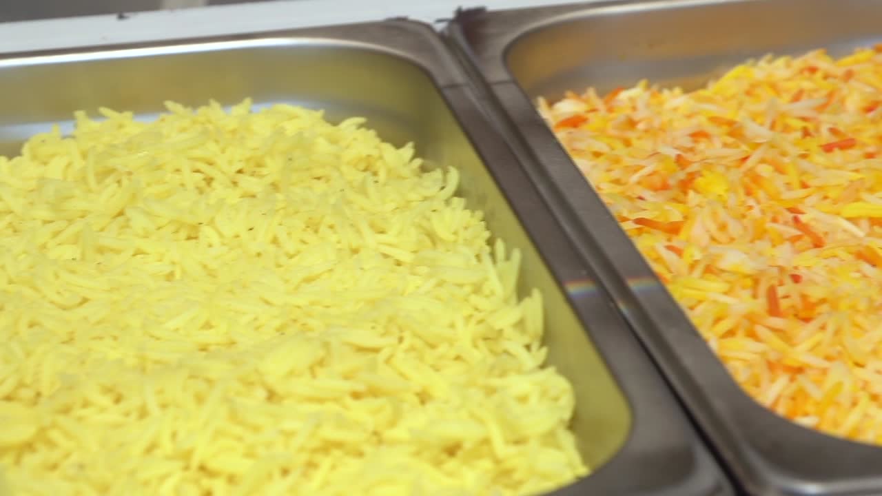 Two kinds of saffron rice in buffet serving containers