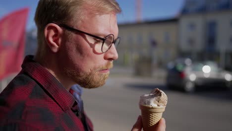 Hombre-Caucásico-Con-Gafas-Y-Pelo-Corto-Come-Helado-En-Un-Día-Soleado,-Cierra