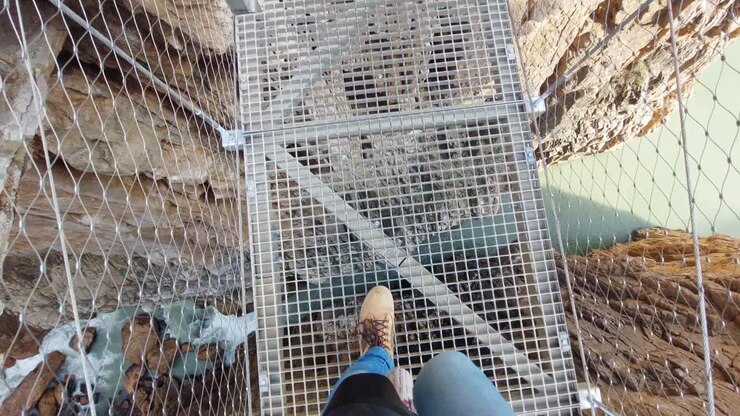 Legs of a person walking on a suspension bridge