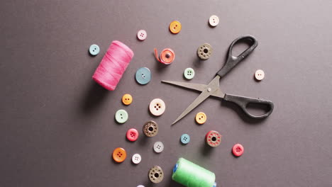 video of scissors with buttons and cotton reels on dark grey background