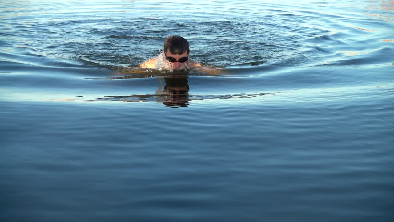 El hombre nada en el mar al atardecer de verano. Cámara lenta