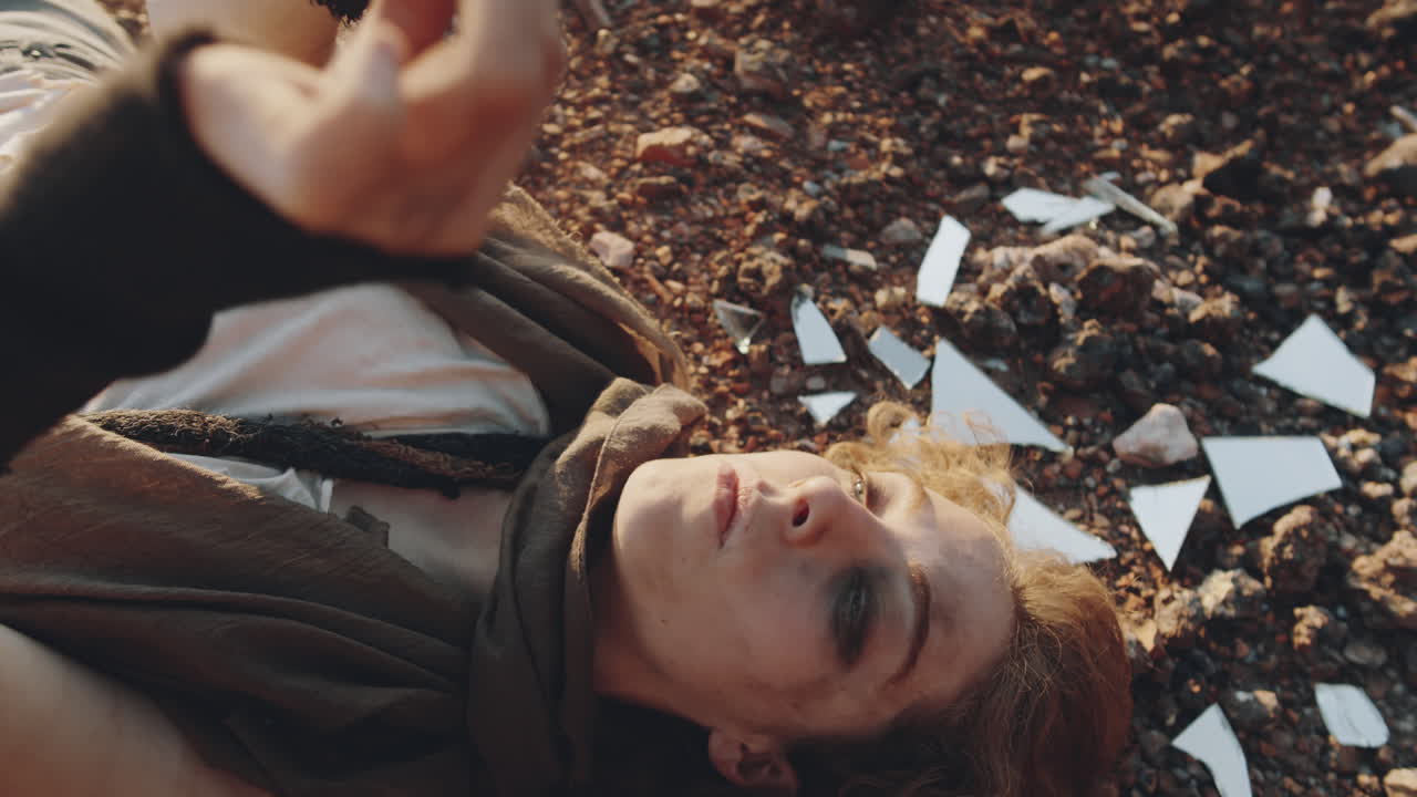 mujer acostada entre piezas de espejo roto en un mundo distópico