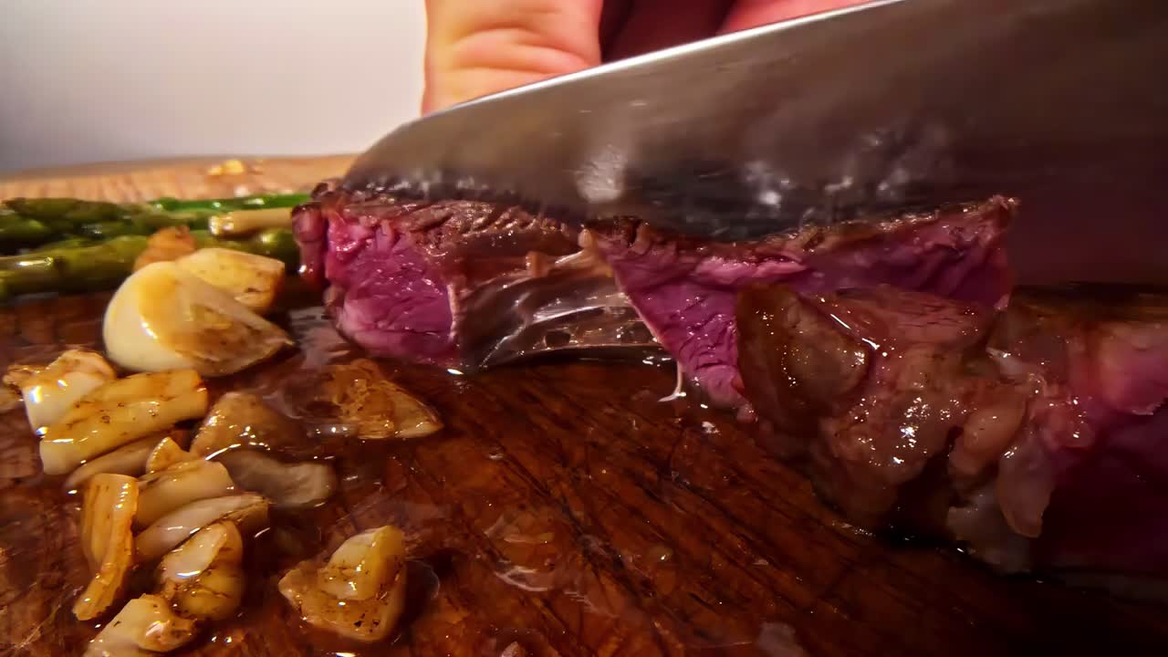 Una succosa bistecca al sangue viene tagliata su un tagliere di legno - Primo piano