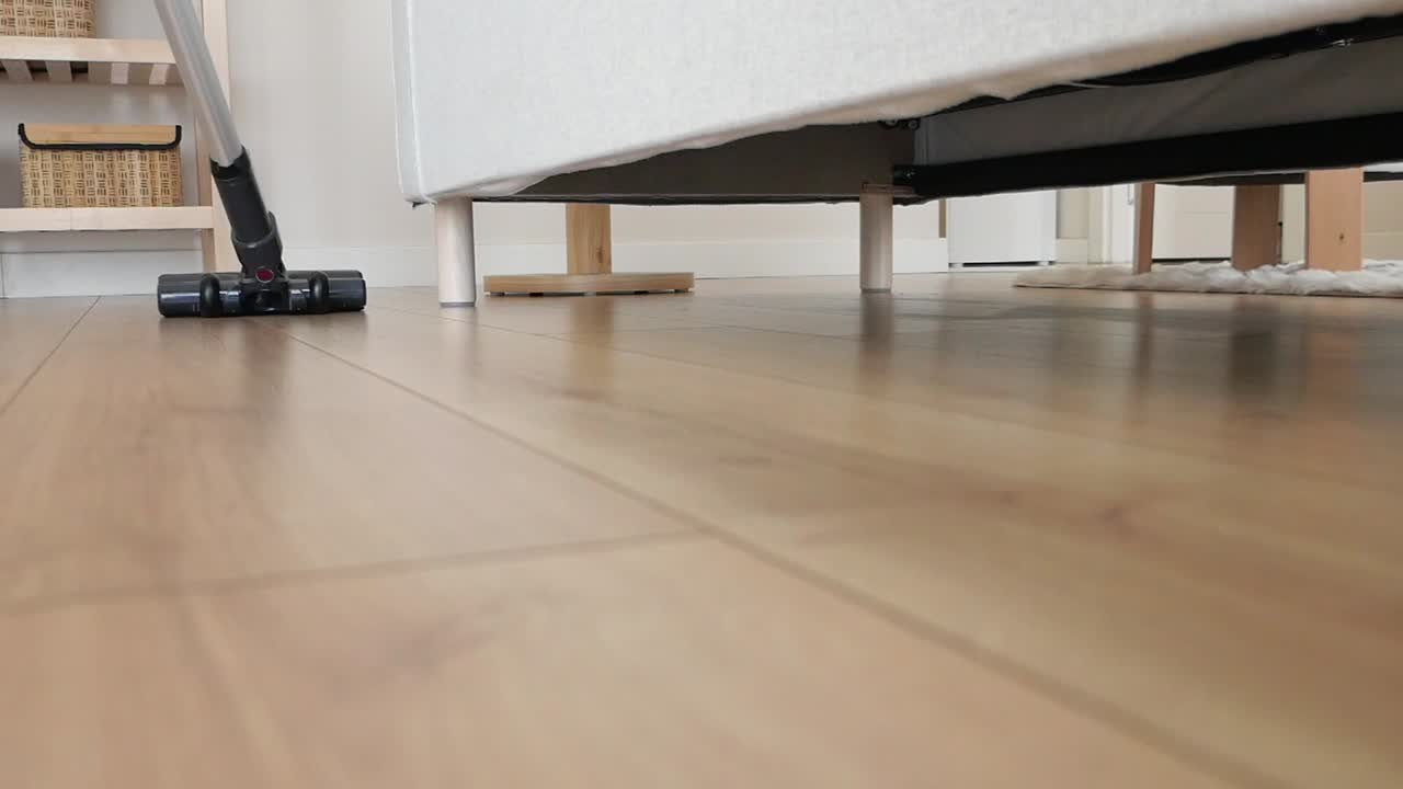 Vacuuming a wooden floor under furniture