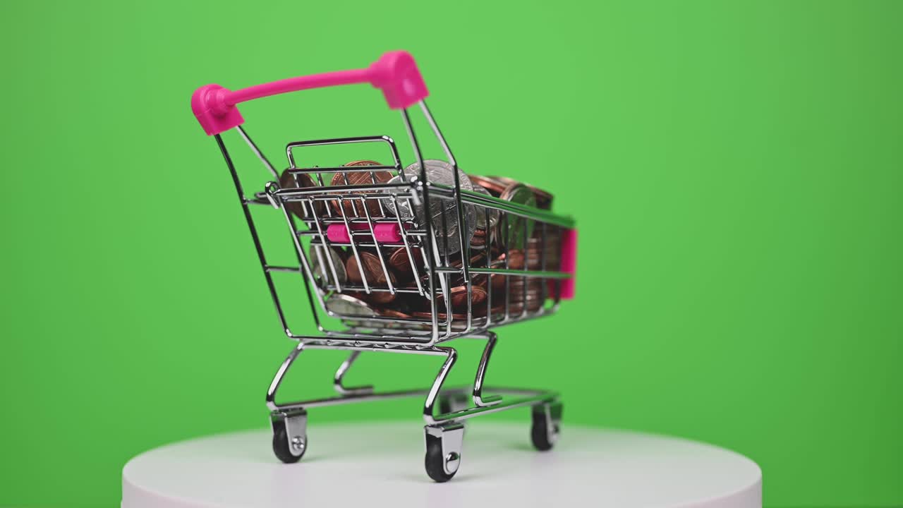 ein spinnender einkaufswagen voller münzen auf dem grünen bildschirm