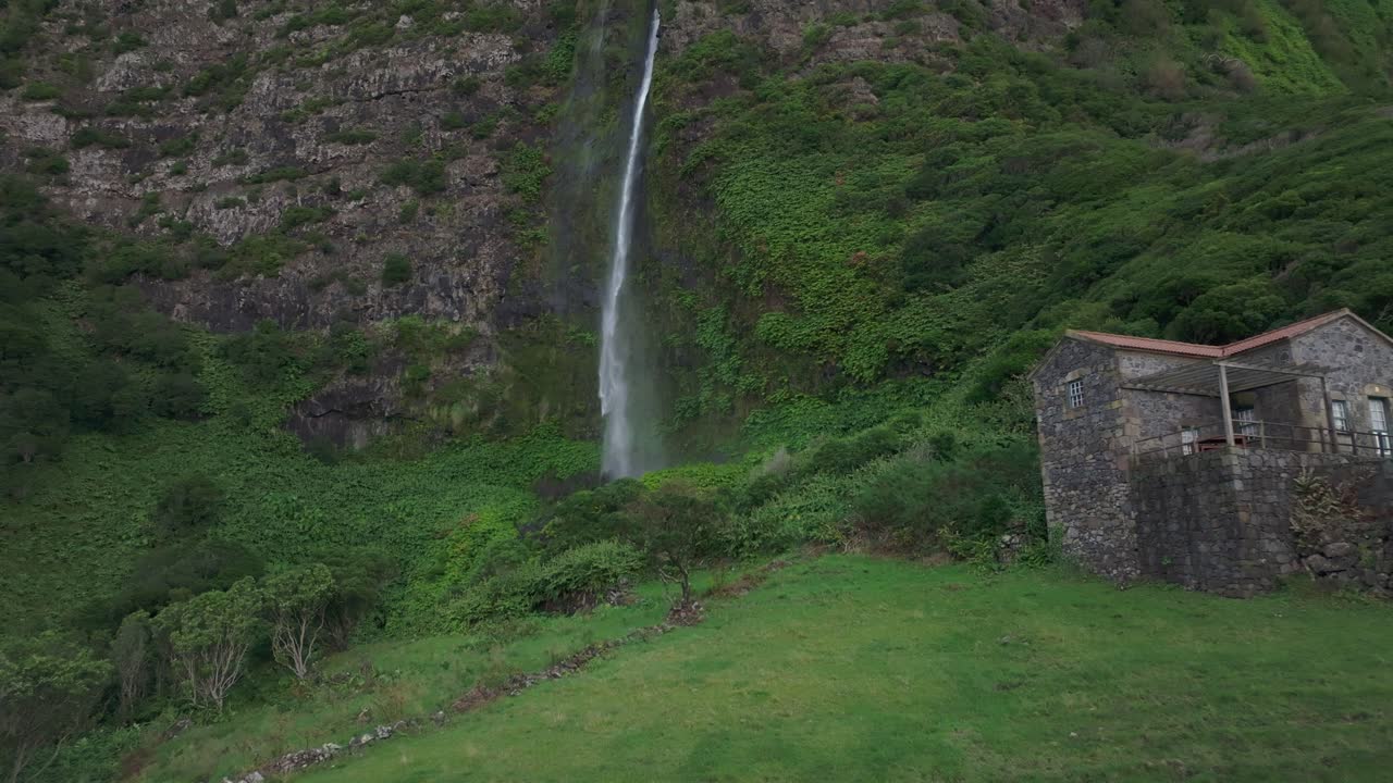 Volando verso la cascata do poço do bacalhau con una casa sull'isola di Flores - Ripresa con drone