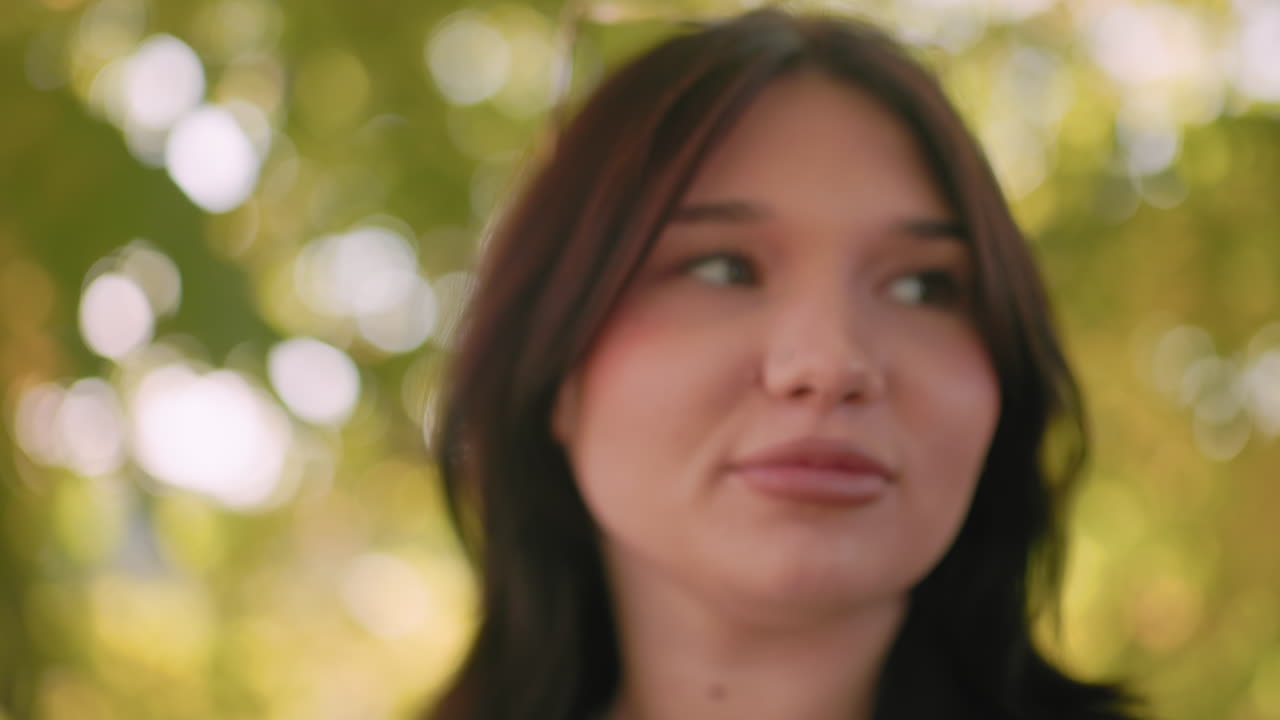 Side view of carefree walker under autumn canopy, gazing upward with soft smile, bokeh background glowing, black coat and sweater visible, gentle breeze, warm sunlight filtering leaves