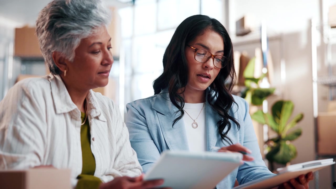 Two Professional Women Reviewing Documents in a Warehouse Office