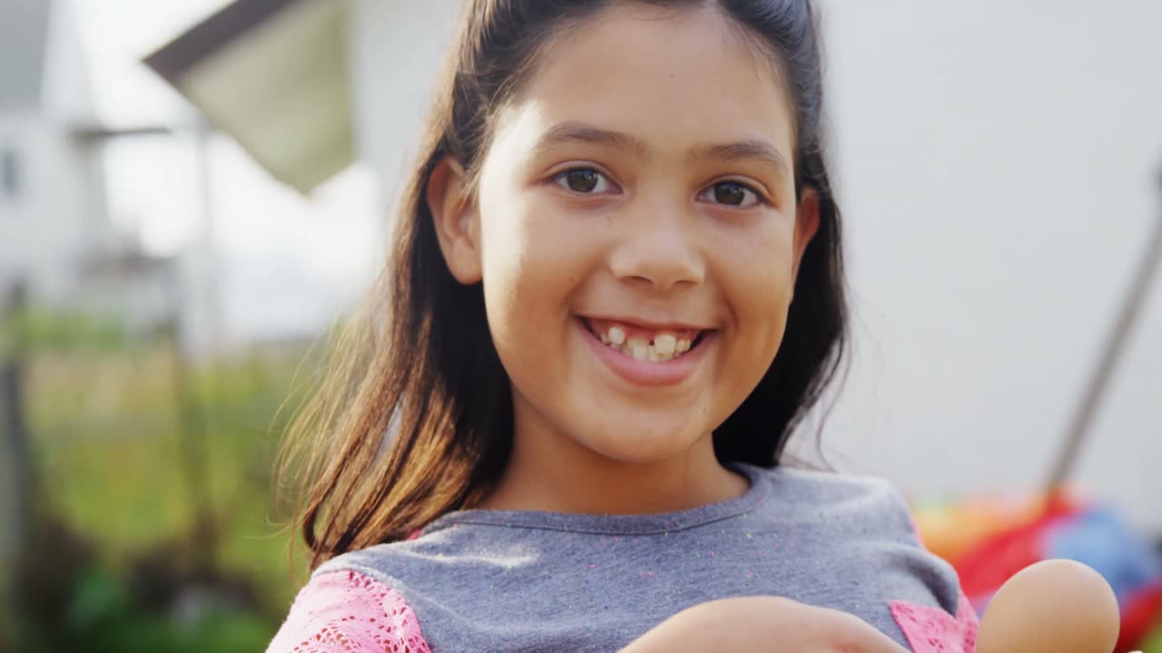 Happy girl holding egg and spoon in backyard 4k